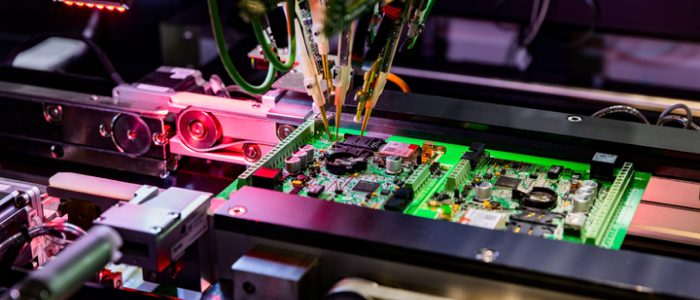 Automated PCB assembly line with robotic probes inspecting electronic components under LED lighting