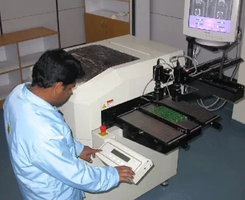 Technician operating automated PCB testing machine for electronic board inspection and quality assurance