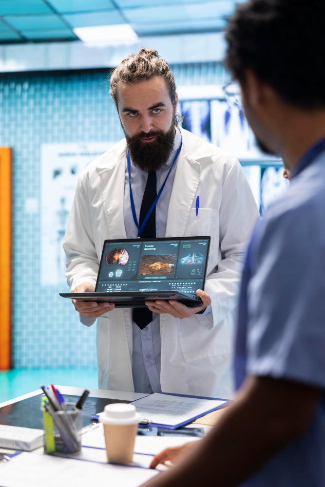 Doctor showing tumor scan on laptop to colleague in medical lab