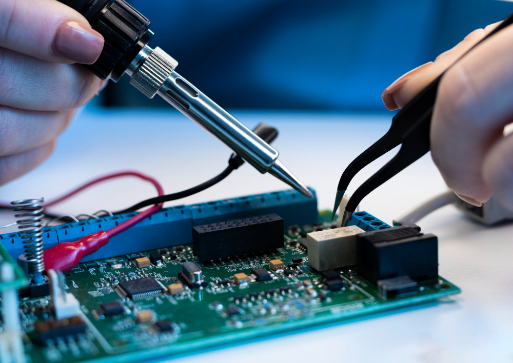 Hands soldering electronic components on a circuit board using a soldering iron and tweezers