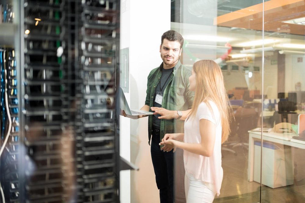 IT professionals discussing server infrastructure near data center racks in a modern office environment