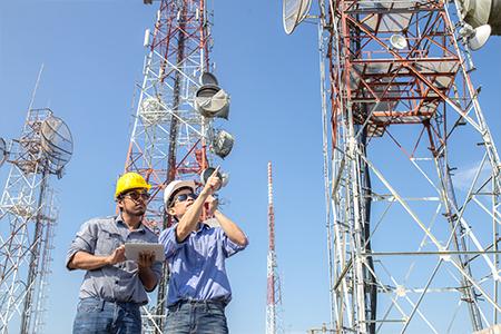 Telecom engineers inspecting and maintaining communication towers at a network site